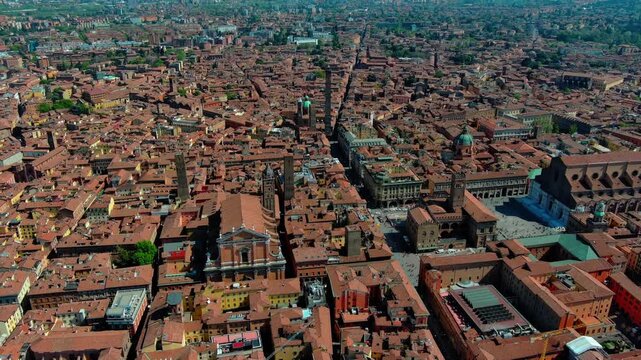 Aerial drone view of Bologna's historic center showing Due Torri towers, terracotta rooftops, and Piazza Maggiore in Emilia-Romagna, Italy, captured in daylight.