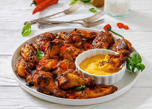 Char-grilled chicken wings on a plate with sauce