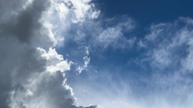 A spectacular cloudscape with dark thunderclouds and thin white clouds against a deep blue sky, a background dedicated to weather and nature