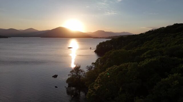 Aerial drone shot of Loch Lomond along the West Highland Way in Scotland. The drone does a push forward over the lake with mountains nad small islands in the background.