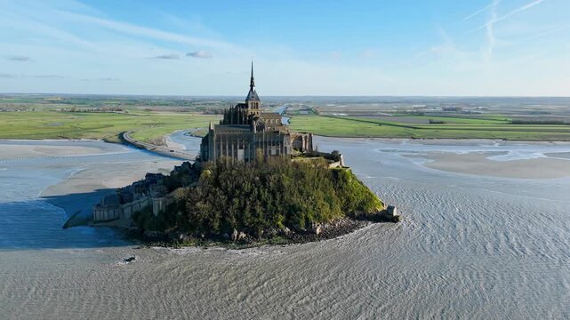 Mont Saint-Michel abbey on tidal island in Normandy, France. Aerial drone view of famous French landmark surrounded by low tide bay and coastal landscape