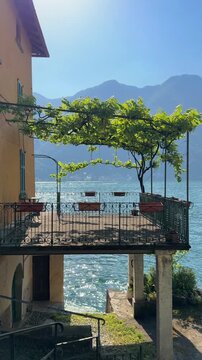 Terrace with vineyard above a lakeside home overlooking Lake Como, Italy. Cozy outdoor seating with panoramic views of the lake and surrounding mountain villages in a peaceful luxury setting