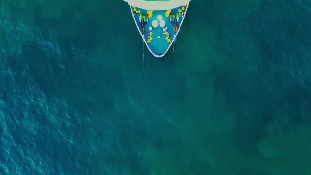 Overhead aerial shot of a passenger and cargo ship anchored alongside a narrow jetty.
