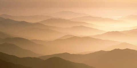 Fototapeta premium Serene layered mountain landscape at sunset with golden haze and atmospheric perspective