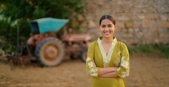 Indian young adult gen z villager female staff fold hand look camera standing visit rural area. Happy proud girl officer cross arm staring cam do casual pose enjoy new day village ground place