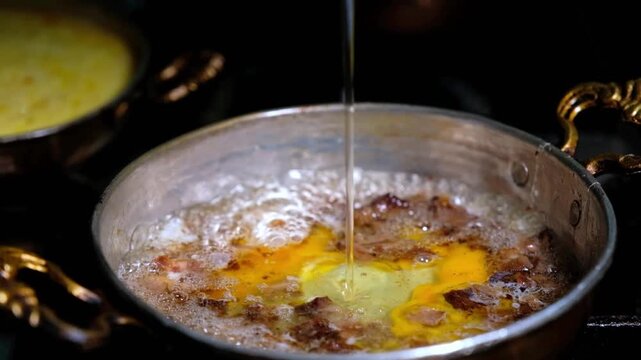 Kavurma and eggs cook together in a copper pan. Close-up scene showing Turkish breakfast presentation, a hot pan dish and traditional eggs with kavurma preparation.