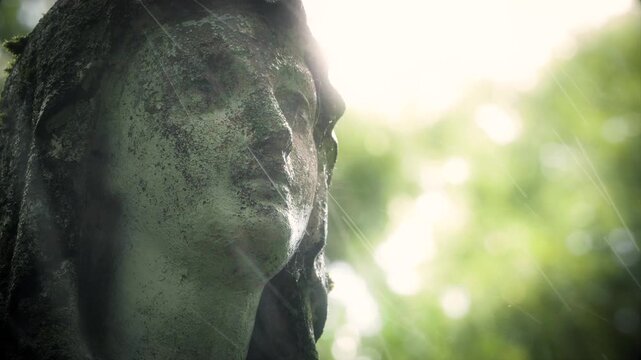  close-up of weathered St. Mary statue face  during rainfall at Bernardine Cemetery.Vilnius, Lithuania
