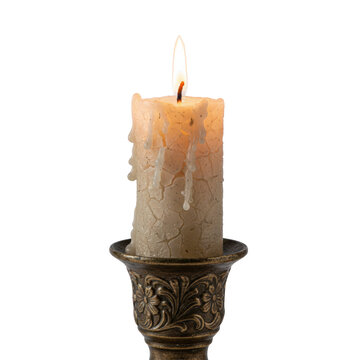 Rustic cylindrical paraffin wax candle with textured cracks and a glowing flame set in an ornate tarnished bronze holder against a white background, serene atmosphere