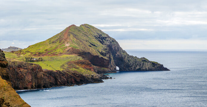 A high-angle view of the deep blue sea meeting a distant flat rocky island from the slopes of Ponta de Sao Lourenco, Madeira, Portugal.