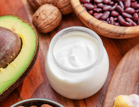 A bowl of fresh white yogurt on a wooden table with different food