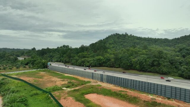 Highway traffic flows alongside a lush green forest landscape