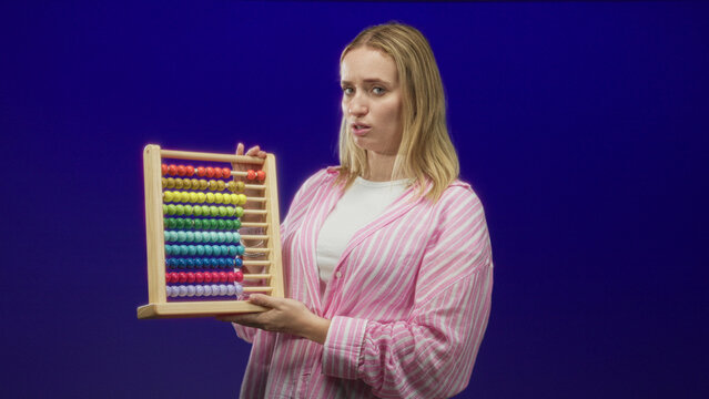 Woman holding abacus, hand gripping wooden frame, pursed lips expression in studio; frustration learning struggle.