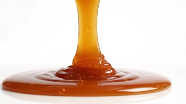 Smooth, rich caramel sauce flowing and swirling, creating a decadent texture against a clean white background.