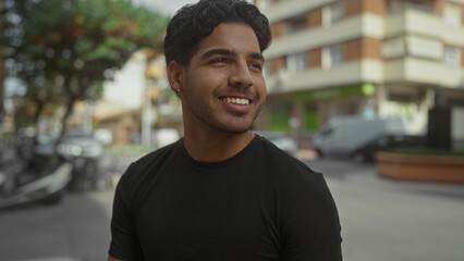 Fototapeta premium Man smiling with visible earring and teeth, head turned to side while standing on a busy street with scooters and buildings in view; carefree joy.