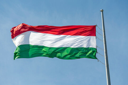 Hungarian flag waves in the wind against a clear sky with no clouds during a sunny day