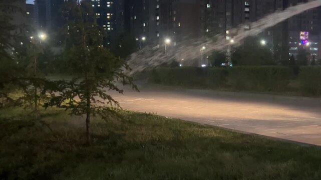 Urban park illuminated at night with city buildings in the background. evening landscape, public space, modern city.