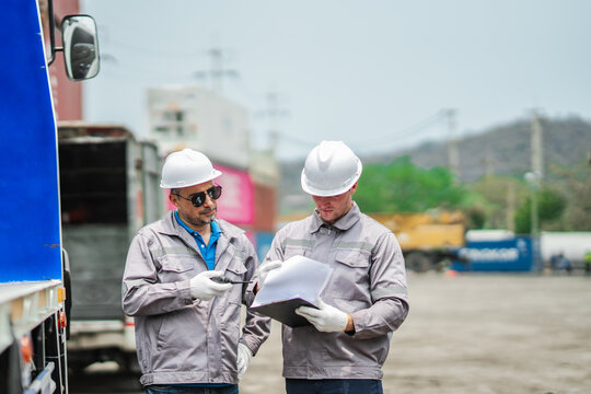 Transportation professionals verify shipment documentation and cargo status beside truck loading area, ensuring compliance, tracking accuracy and smooth freight operations.