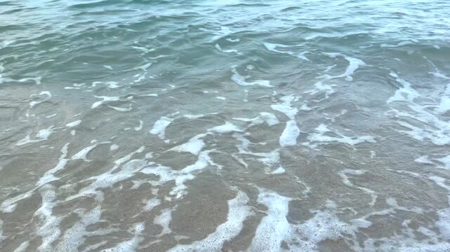 Soft sea waves roll across the shoreline, creating natural patterns of foam and movement. Perfect concept for relaxation, vacation, wellness, mindfulness, coastal travel, and summer lifestyle.