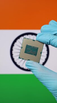Close up view of hand in blue glove holding CPU microchip. Indian flag in blurred background. Concept of semiconductor shortage and artificial intelligence development in India.
