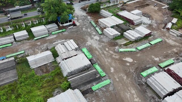 A view from above of stacked precast concrete blocks and heavy machinery at a building materials storage yard.