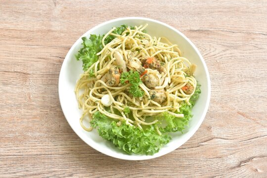 spicy stir fried spaghetti with scallop in garlic butter sauce with vegetable salad on plate 