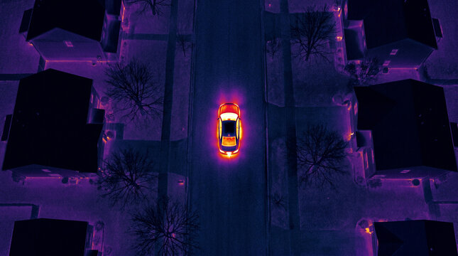Thermal imaging view of car driving on suburban street at night with infrared camera heat map infrared
