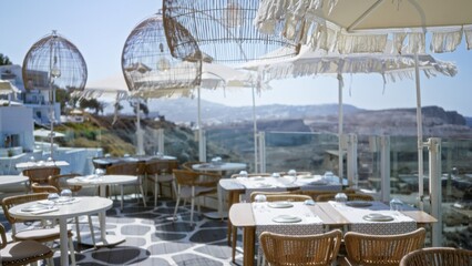 Obraz premium Sunlit terrace dining scene softly blurred with shallow bokeh and defocused coastal view, cafe; background backdrop copyspace calm.