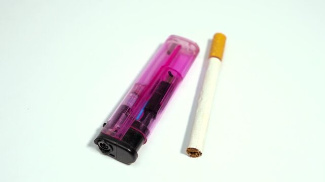Pink cigarette lighter next to a single cigarette smoking tobacco plastic fire flame smoking tobacco plastic fire flame