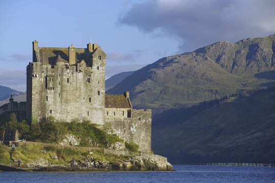 A majestic waterfront castle with mountains in the background under a dramatic sky, film set, Highlander, James Bond, Rob Roy, Eilean Donan Castle, Scotland, Great Britain