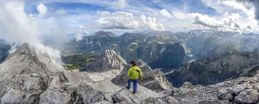 Mountaineer on the rocky summit of the Watzmann Mittelspitze, Watzmann crossing, view of mountain panorama with Steinernes Meer and K&ouml;nigssee, Berchtesgaden National Park, Berchtesgaden Alps, Bavaria, Germany