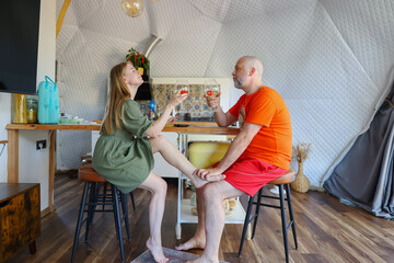 Fototapeta premium Romantic evening in a modern geodesic dome with a couple toasting wine during a cozy vacation retreat.