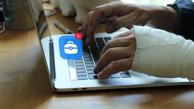 Injured East Asian man with a bandaged hand typing on laptop keyboard, with a 3D tracked professional business briefcase notification pop up badge and red counter.