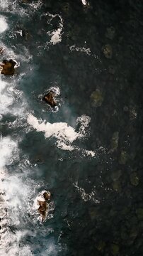 Top view of ocean waves breaking over rocks with white foam patterns. Atlantic water surface texture in motion
