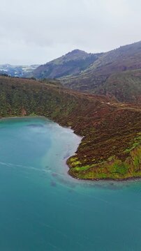 Crater lake in Azores with peninsula and calm water inside volcanic basin. Lagoa do Fogo aerial shot with cloudy sky