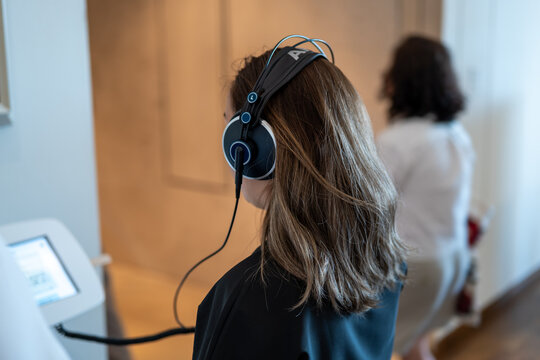 Woman listens to an audio guide through headphones while visiting a museum exhibition.