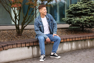 Obraz premium Young man in stylish denim outfit on bench outdoors