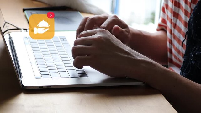 Close up of an Asian man hands typing on a laptop keyboard in casual wear, showing a 3D tracked restaurant food cloche catering butler menu notification pop up and red counter.