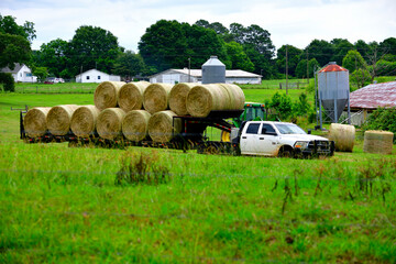 Truck at a farm gathering bales of hay © itsallgood