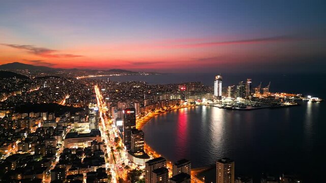 Aerial coastal city skyline at sunset with illuminated buildings