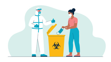 Fototapeta premium Hazmat worker giving a thumbs up while a woman discards her used face mask into a yellow biohazard waste container.