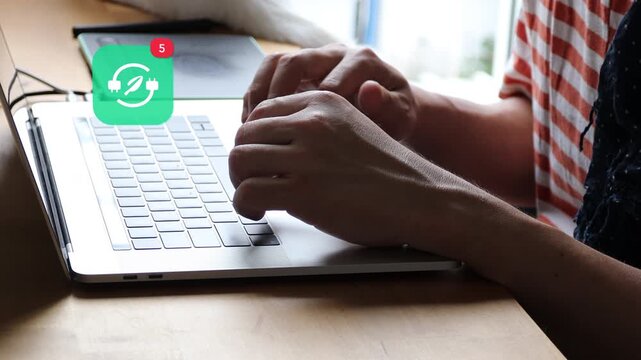 Casual Asian man hands typing on a laptop computer keyboard, with a 3D tracked eco green leaf electric plug power notification pop up and red counter.