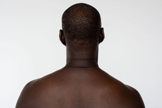 Back view of a shirtless Black man against a plain white background