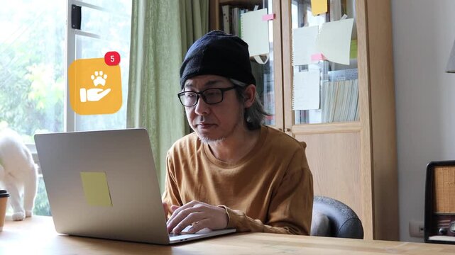  A mature Asian man with long white hair and glasses typing on a laptop at home, showing a 3D tracked hand holding pet animal paw footprint notification pop up and red counter.
