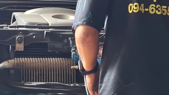 Professional auto mechanic calmly inspecting and servicing a vehicle air conditioning system in a modern, well-equipped auto repair garage.
