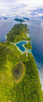 Aerial view of the lush green islands and turquoise lagoons of Raja Ampat Regency in Southwest Papua, Indonesia.
