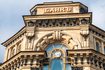 Naklejka premium Moscow, Russia - May 21, 2026: Historic bank building showcases intricate architectural details and a clock, with the word BANK clearly visible on the facade