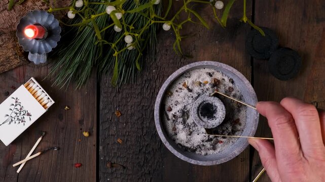 Top view of incense burning on glowing charcoal - placing incense with a spoon