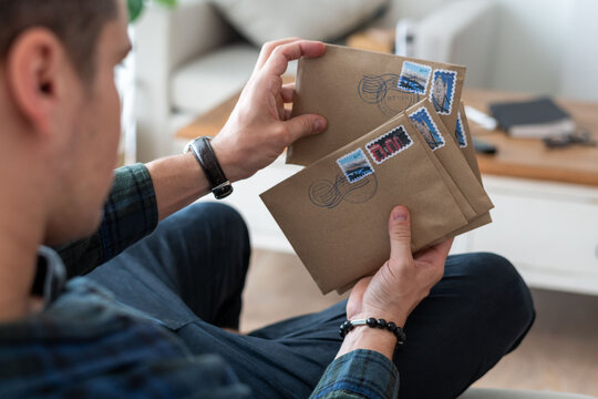 Man holding several stamped envelopes.