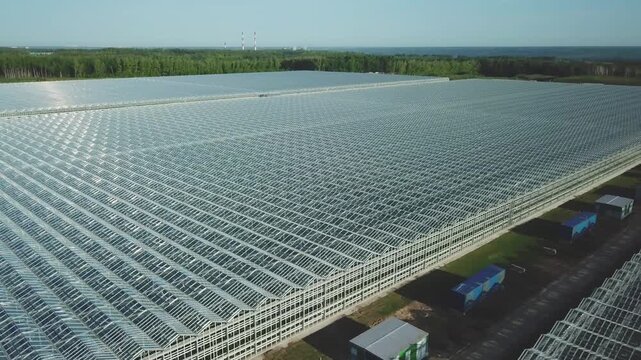 Drone flying sideways and backward over greenhouse roofs