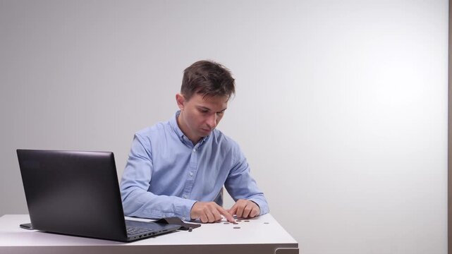 Sad man sitting at a desk and checking his empty wallet, finding only a single coin, reflecting financial difficulties and money problems while working from home